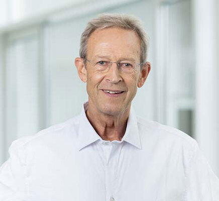 Porträtbild Dr. Alexander Kirgis, weißes Hemd, lächelnd, heller Hintergrund