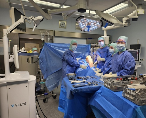 OP-Team während einer Knieoperation im Operationsaal, vier Ärzte und Assistenzkräfte am OP-Tisch