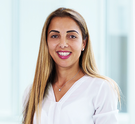 Portrait Zuhal Hube, Mitarbeiterin im International Office der OCM, weiße Bluse, lächelnd