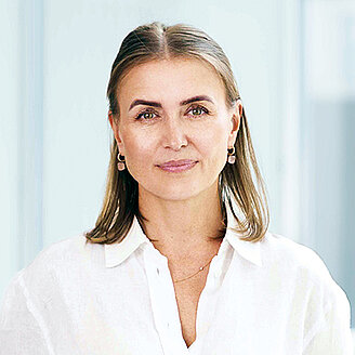 Portrait Marina Schlegel, Head of International Office in der OCM, weiße Bluse, freundlicher Gesichtsausdruck