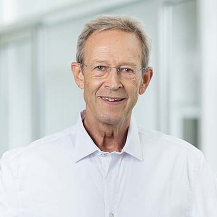 Portraitfoto Dr. Alexander Kirgis, lächelnd, weißes Hemd, Arzt der OCM Orthopädische Chirurgie München