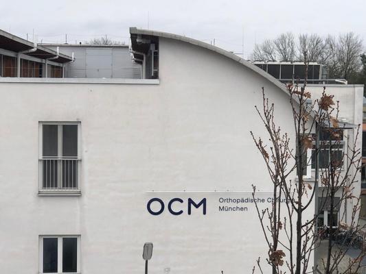 seitliche weiße Hauswand mit Schild OCM