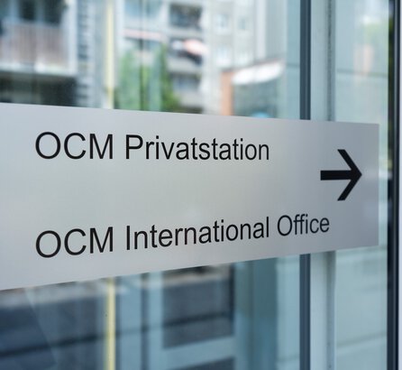 Eingangstürschild zum International Office der OCM, silberfarben mit schwarzer Schrift
