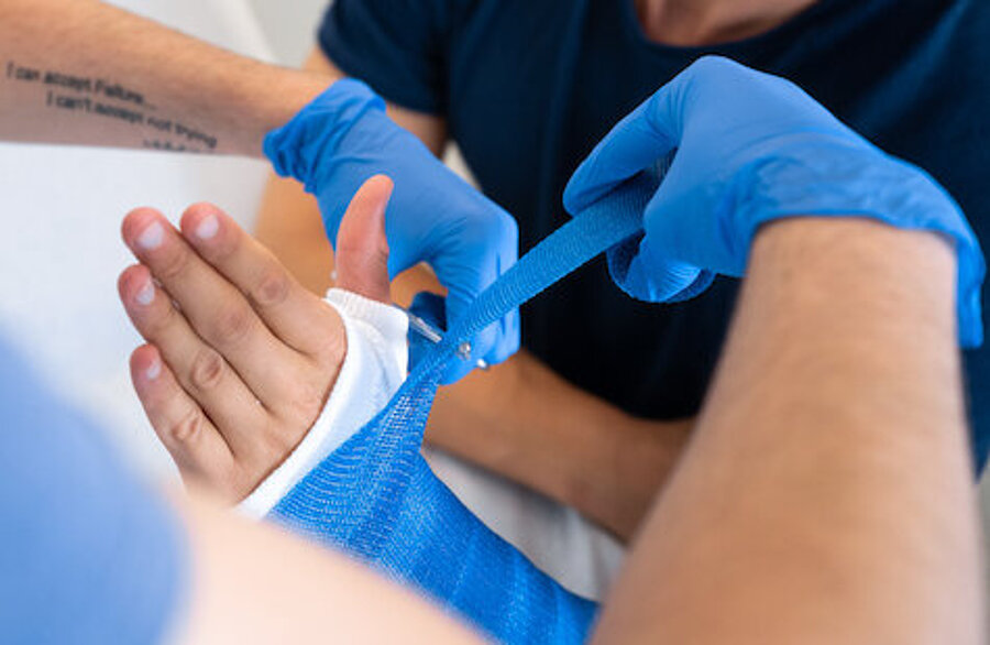 Knochenbruch am Arm eines jungen Patienten wird behandelt, Gipsverband ansatzweise sichtbar